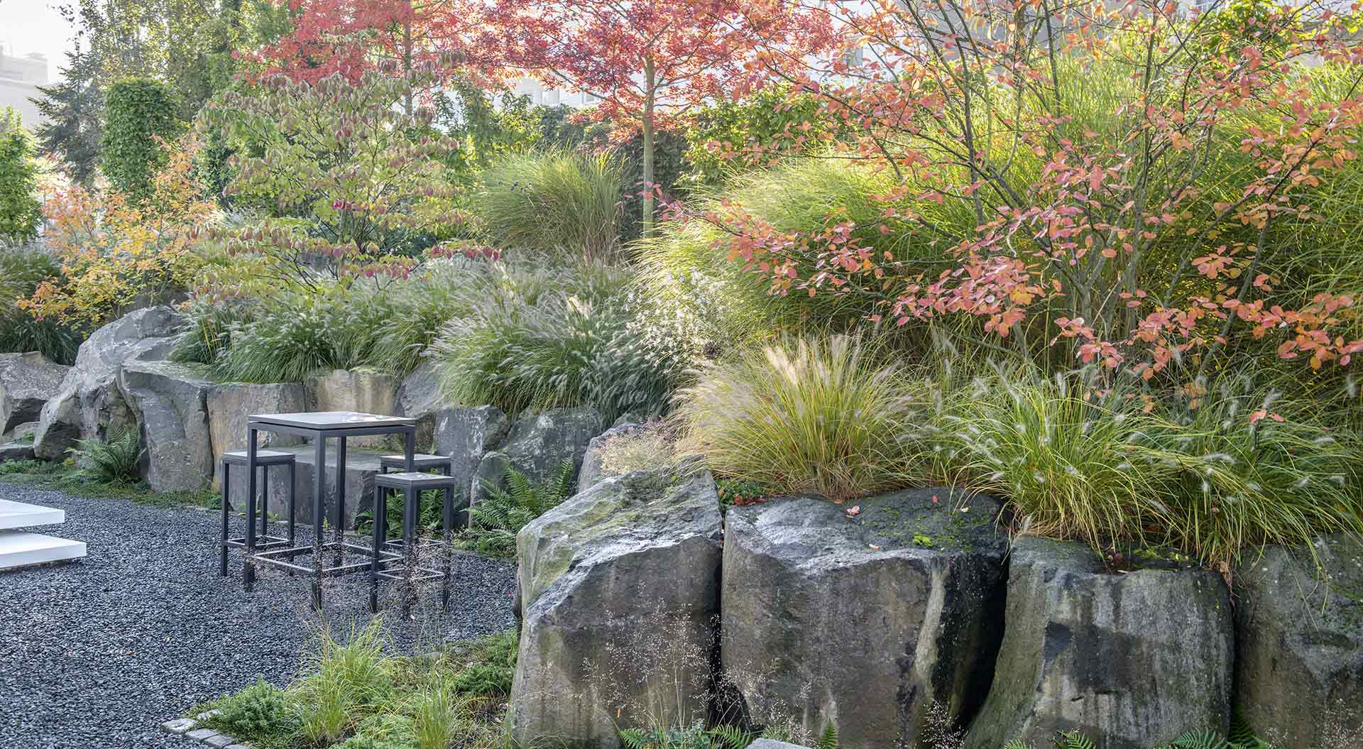 Slope garden with a big stone wall and a high amount of grasses